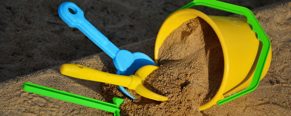 A plastic bucket and spade set on the beach.
