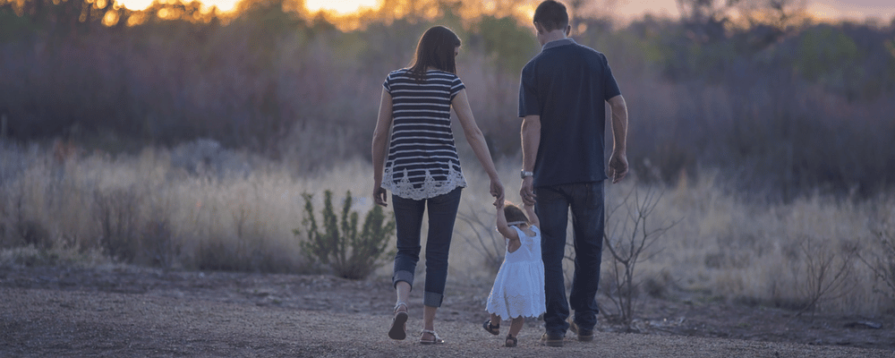 Stock photo of a man, woman and child walking hand in hand.
