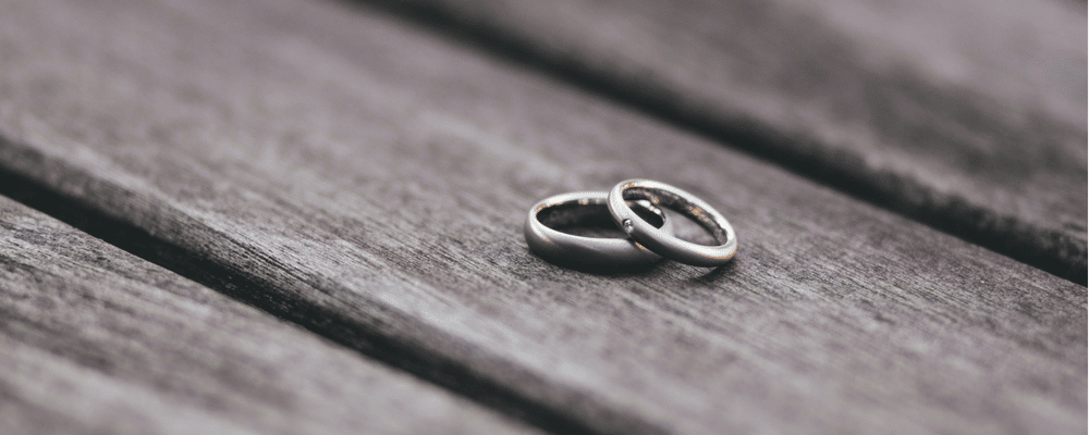 Two discarded wedding rings on a table to illustrate divorce