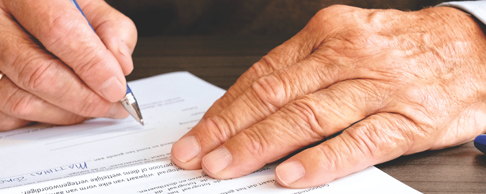 A legal document being signed by an older person