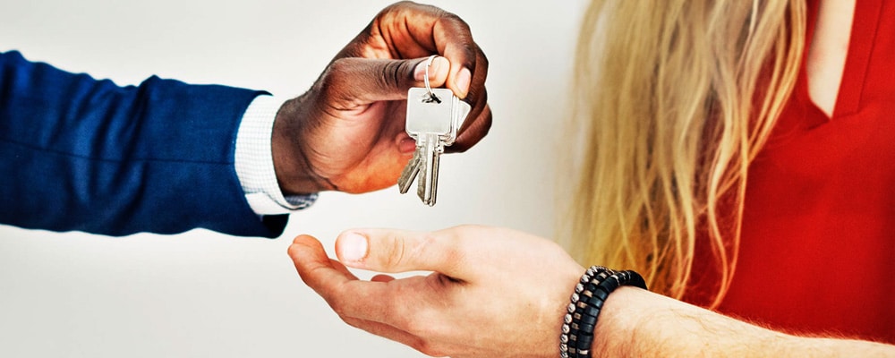 A man handing a women a set of keys