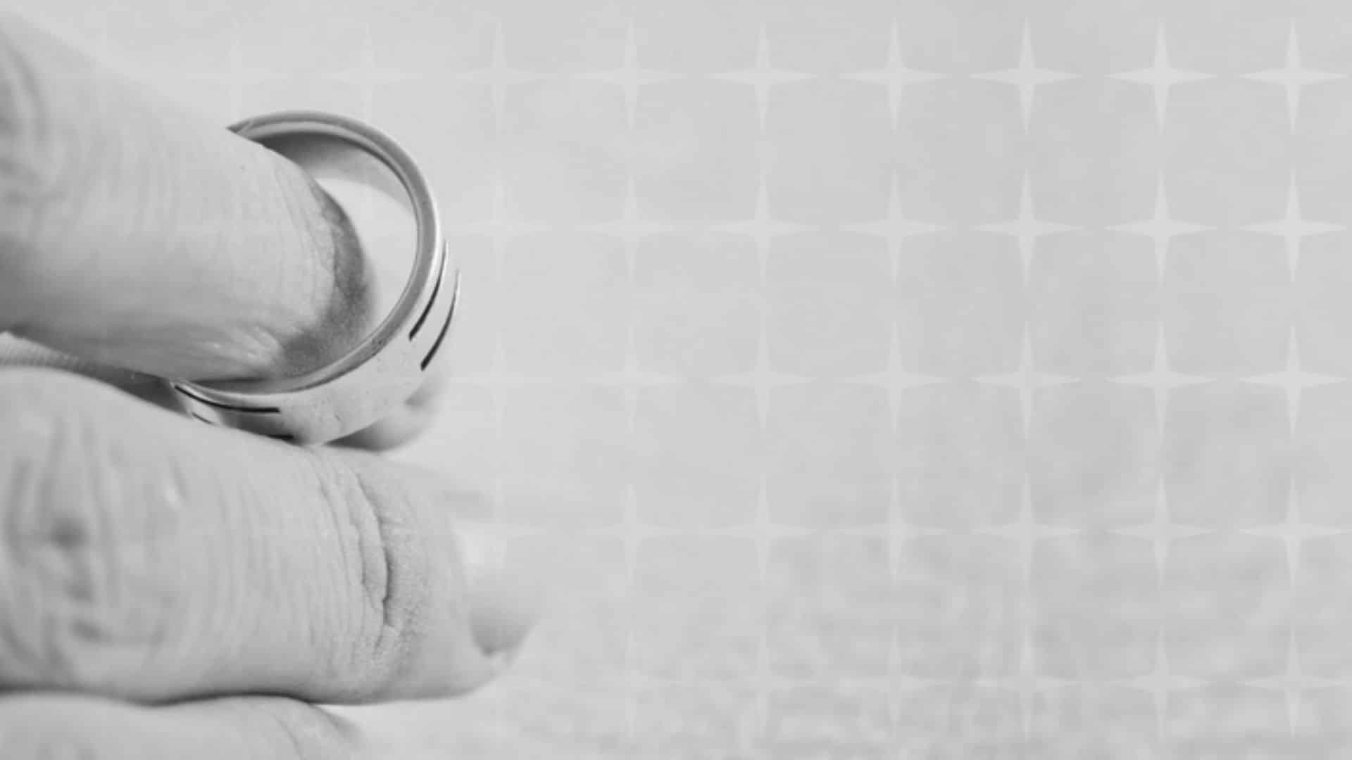 black and white photo of a wedding ring being held between two fingers