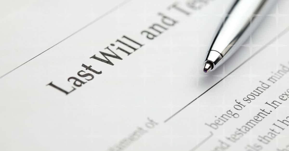 An image of a Last Will & Testament with a silver pen laid on top.