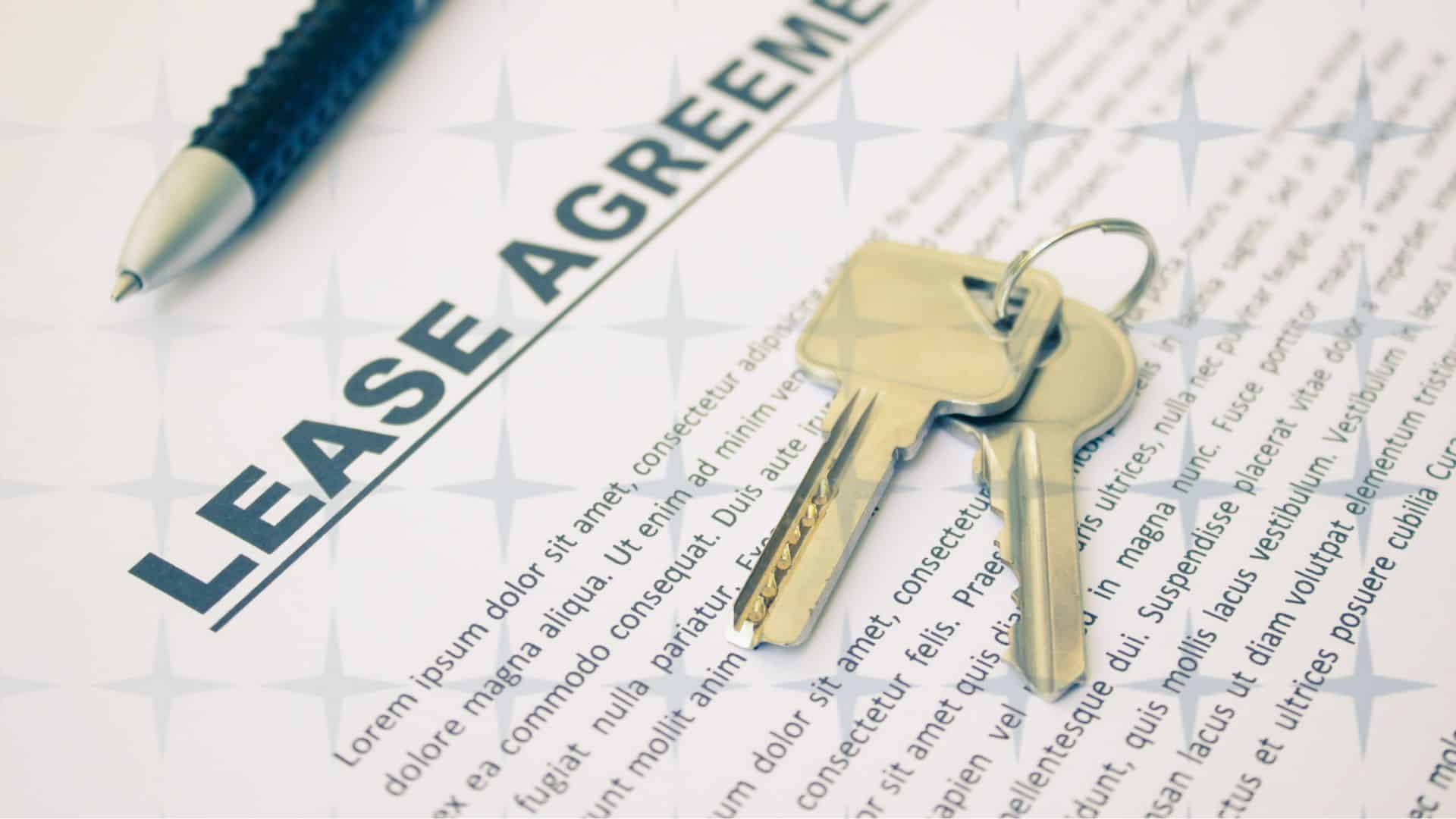 A pen and set of keys resting on a legal document entitled 'Lease Agreement' to help illustrate a commercial property lease agreement.